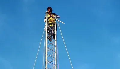 Image description: A person high up on a communications tower. Image source: Village Base Station Project, University of the Philippines image linking to Community Networks and Local Access Monthly Newsletter - Number 14
